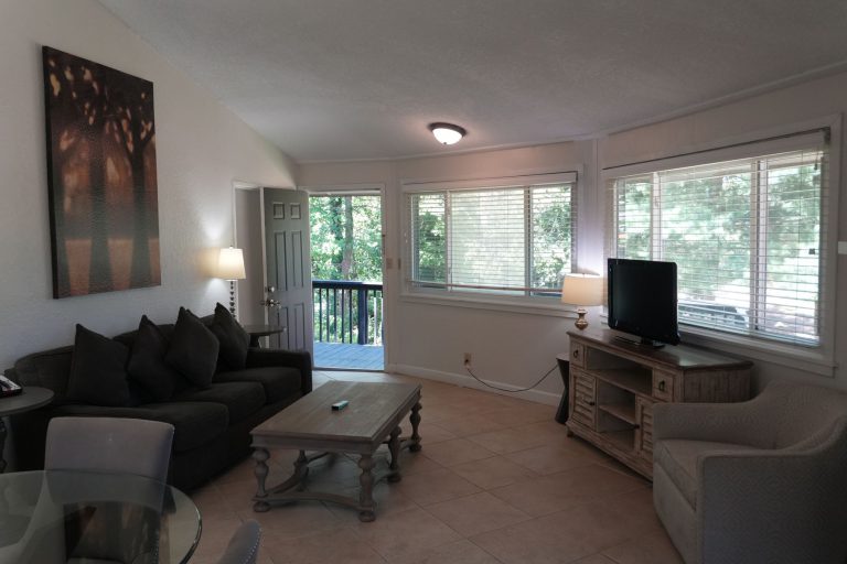 Living room with a sofa, armchairs and windows opening onto the deck