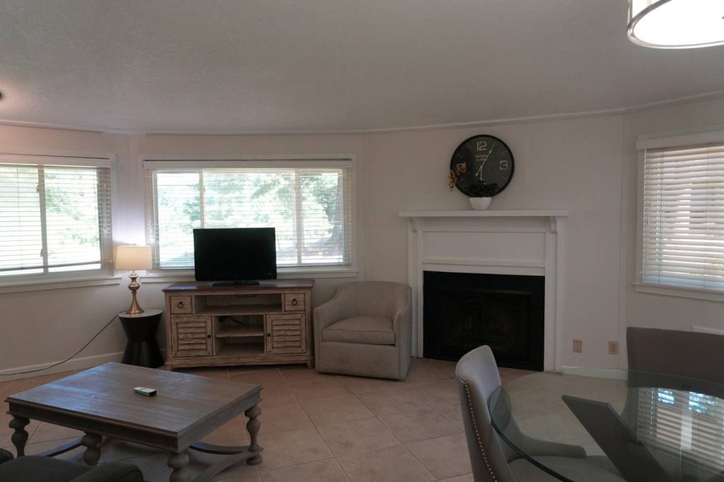 Sitting area with a white fireplace, TV console and armchair