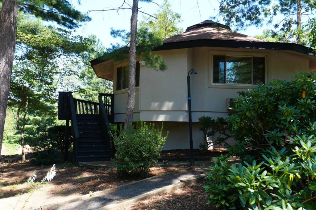 A cedar-shingled octagonal villa building among the pines